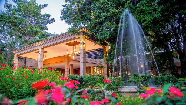 Ein Hotel mit überdachtem Außenbereich, einer Springbrunnen und üppiger Bepflanzung.