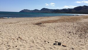 A beach with pebbles and rocks, a clear sky, and mountains in the distance. - Seaside Family Apartment 200 mts from the Beach (Son Serra de Marina)