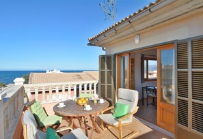 A balcony with a table set for breakfast, a chair, and a view of the sea. - Apartment 'Calabruix' with Sea View, Wi-Fi and Air Conditioning (Son Serra de Marina)
