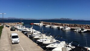 A marina with boats docked, a parking area with a white van, and a clear blue sky. - Seaside Family Apartment 200 mts from the Beach (Son Serra de Marina)