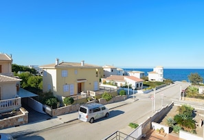 A coastal residential area with a white van parked on the street, houses with balconies, and a clear view of the sea. - Apartment 'Calabruix' with Sea View, Wi-Fi and Air Conditioning (Son Serra de Marina)