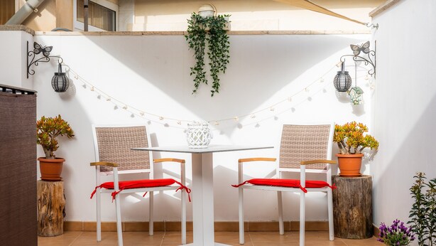 A patio with two white chairs, a white table, string lights, and potted plants. - Apartment Sa Mina with Terrace & Wi-Fi (Santa Margalida)