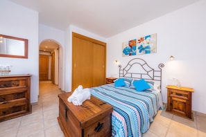 Un dormitorio con una cama, un aparador de madera, una mesita de noche, un espejo y un cuadro en la pared.