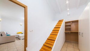 A modern interior with a wooden staircase, white walls, a sofa, and a small table. - Apartment Sa Mina with Terrace & Wi-Fi (Santa Margalida)