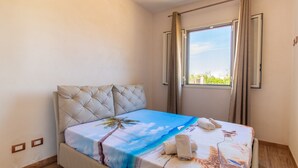 A single bed with a tropical-themed bedspread, a window with curtains, and a ceiling light fixture. - Holiday Home "Casa Vacanza Il Melograno" with 2 Private Terraces, A/C and Wi-Fi (Santa Maria del Focallo)