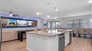 A modern kitchen with a large island, built-in appliances, and pendant lighting.