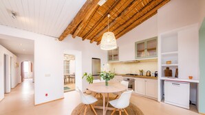 A modern kitchen with white cabinets, a dining table with chairs, and a hanging light fixture.