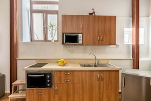 A kitchen with wooden cabinets, a microwave, a sink, and a small refrigerator.
