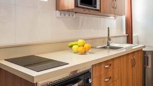 Een keuken met een ingebouwde magnetron, een spoelbak, een vaatwasser en een fruitschaal op het aanrecht.