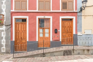A building with three wooden doors, a metal railing, and a stone wall.