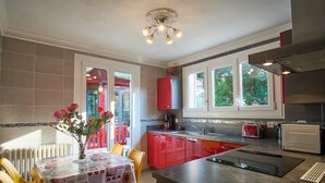 Une cuisine moderne avec des meubles de rangement rouges, un îlot central et un coin repas avec une table mise pour deux personnes.