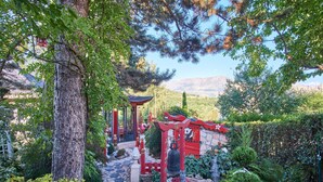 Un jardin japonais traditionnel avec un sentier de pierres, un portail torii rouge et une pagode.
