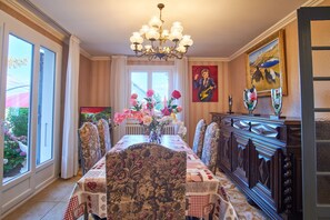 A dining room with a long table, chairs, a chandelier, and a view through a window. - Holiday Home 'Au Printemps Japonais' with Mountain View, Garden, Balcony, A/C & Wi-Fi (Pierre-Châtel)