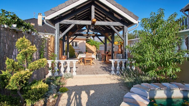 Un patio cubierto con pérgola, mobiliario exterior y una piscina pequeña.