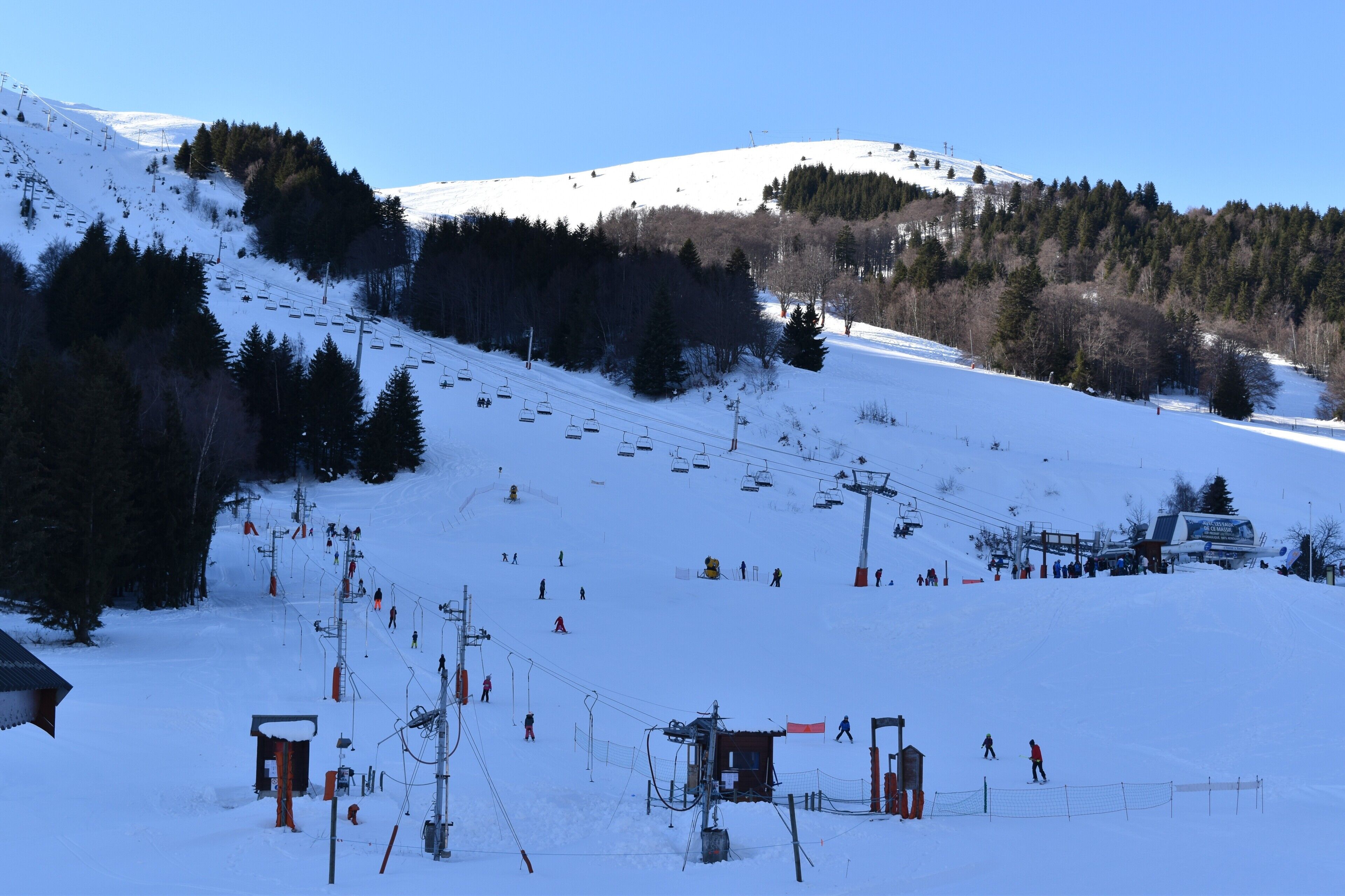 A ski resort with a chairlift, snow-covered slopes, and a forested hill.