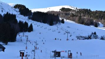 A ski resort with a chairlift, snow-covered slopes, and a forested hill.