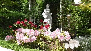 Una estatua en un jardín con flores y un pérgola.