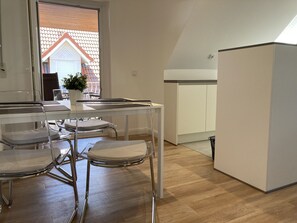 Une cuisine moderne avec un coin repas, comprenant un meuble blanc, une table et deux chaises.