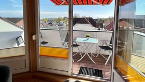A balcony with a table and chairs, a potted plant, and a view of neighboring houses. - Apartment house "Charibi" a well-kept residential complex near the beach (Dahme)