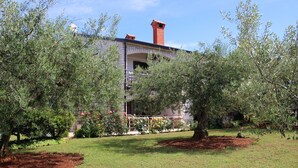 Un bâtiment doté d’une cheminée en briques, entouré d’arbres et d’un jardin bien entretenu.