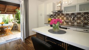 Une cuisine moderne avec des meubles blancs, un îlot central agrémenté d’un vase de fleurs et un coin repas avec une table et des chaises.