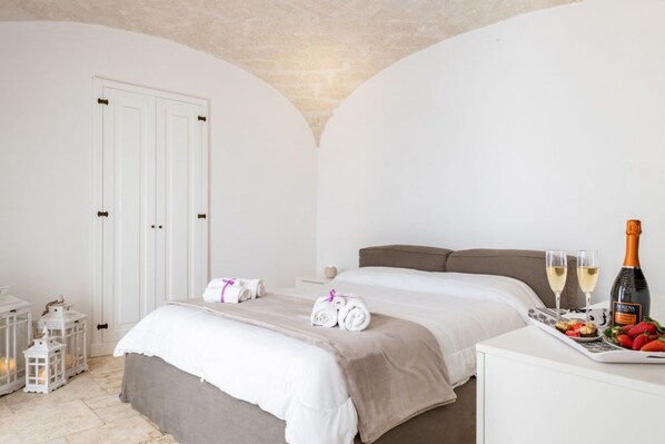 Une chambre à coucher avec un lit, une table de chevet sur laquelle se trouve un plateau avec de la nourriture et des boissons, et une porte dotée d’un porte-serviettes.