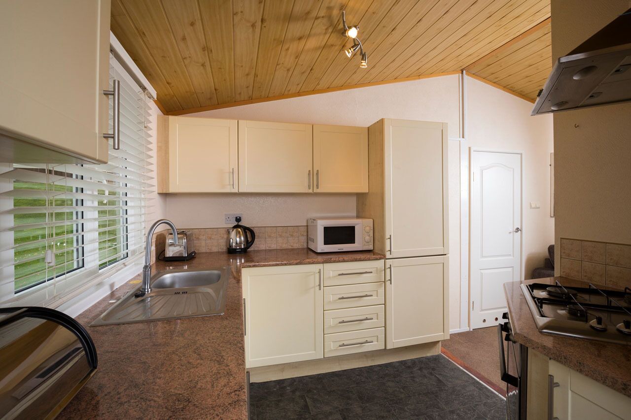 A kitchen with white cabinets, a microwave, a sink, and a stove.