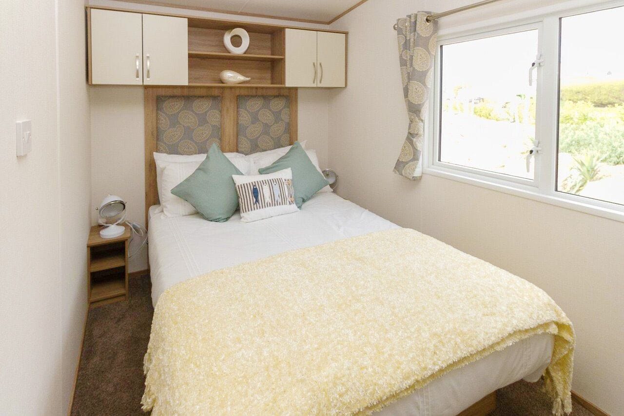 A bedroom with a bed, a bedside table, a wardrobe, and a window with a view.