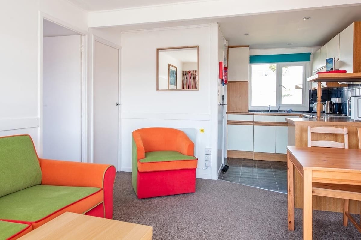 A compact living space with a kitchenette, a dining area, and a colorful seating arrangement.
