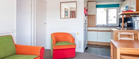 Een knus woongedeelte met een kitchenette, een eethoek en een kleurrijke zithoek.