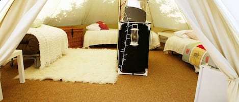Ein gemütliches Zelt mit zwei Betten, einem Kamin und einer karierten Decke.