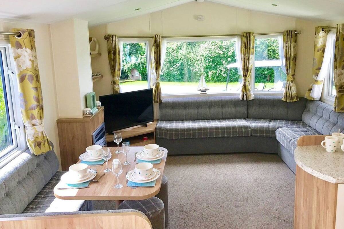 A cozy RV interior with a dining area, a sofa, and a TV.