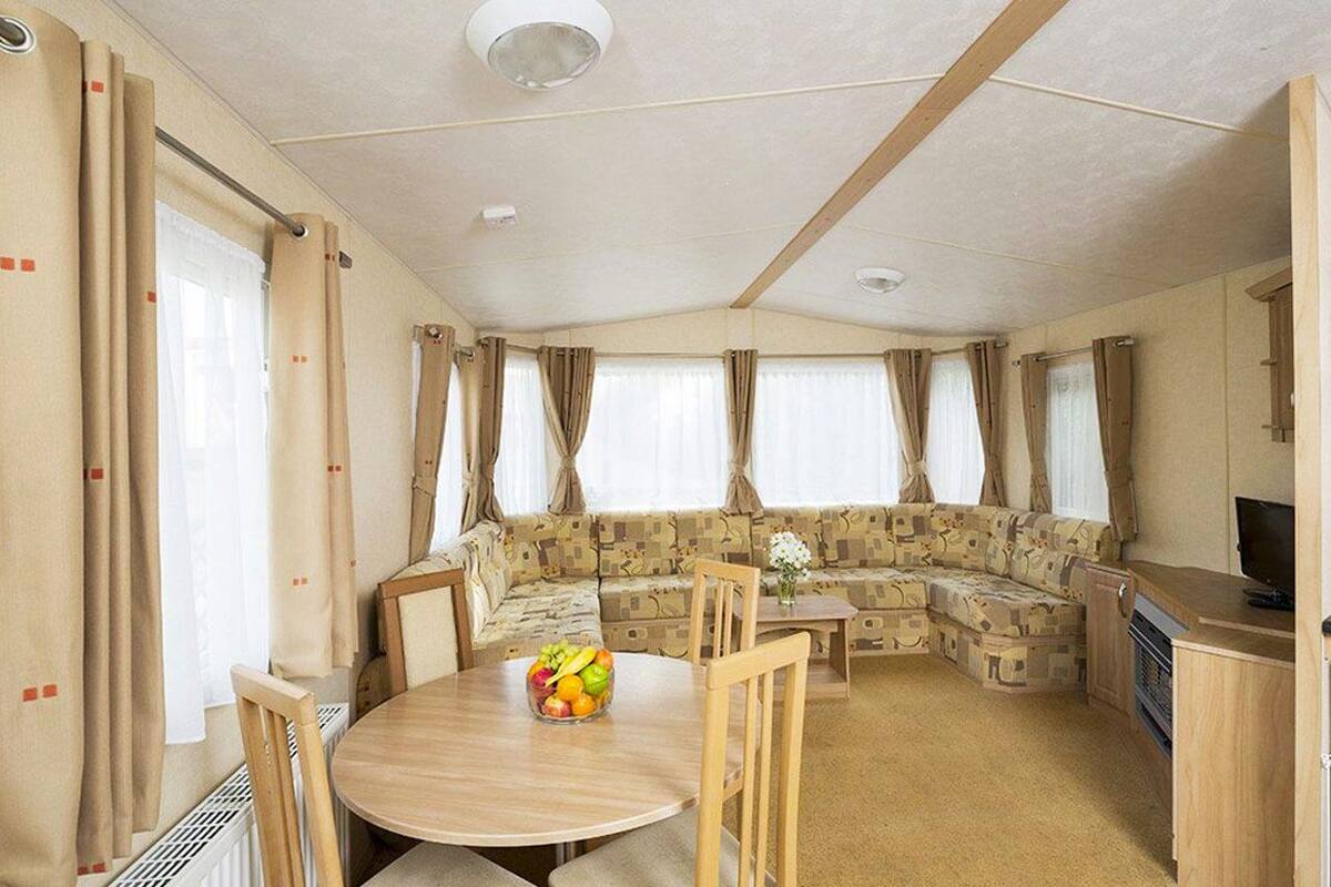 A cozy RV interior with a dining area, a sofa, and a kitchenette.