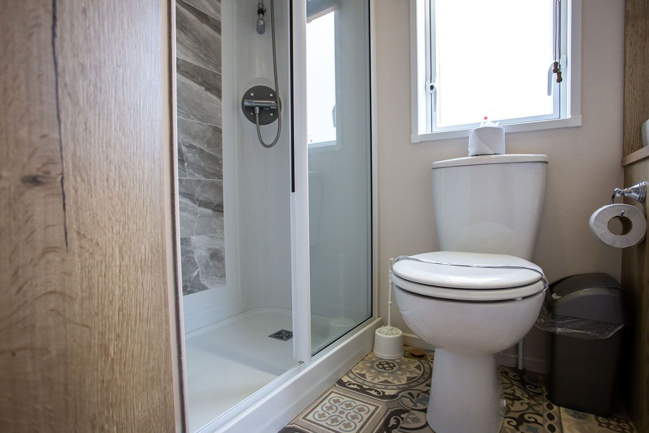 Une salle de bain avec une douche à parois de verre, des toilettes et une fenêtre.