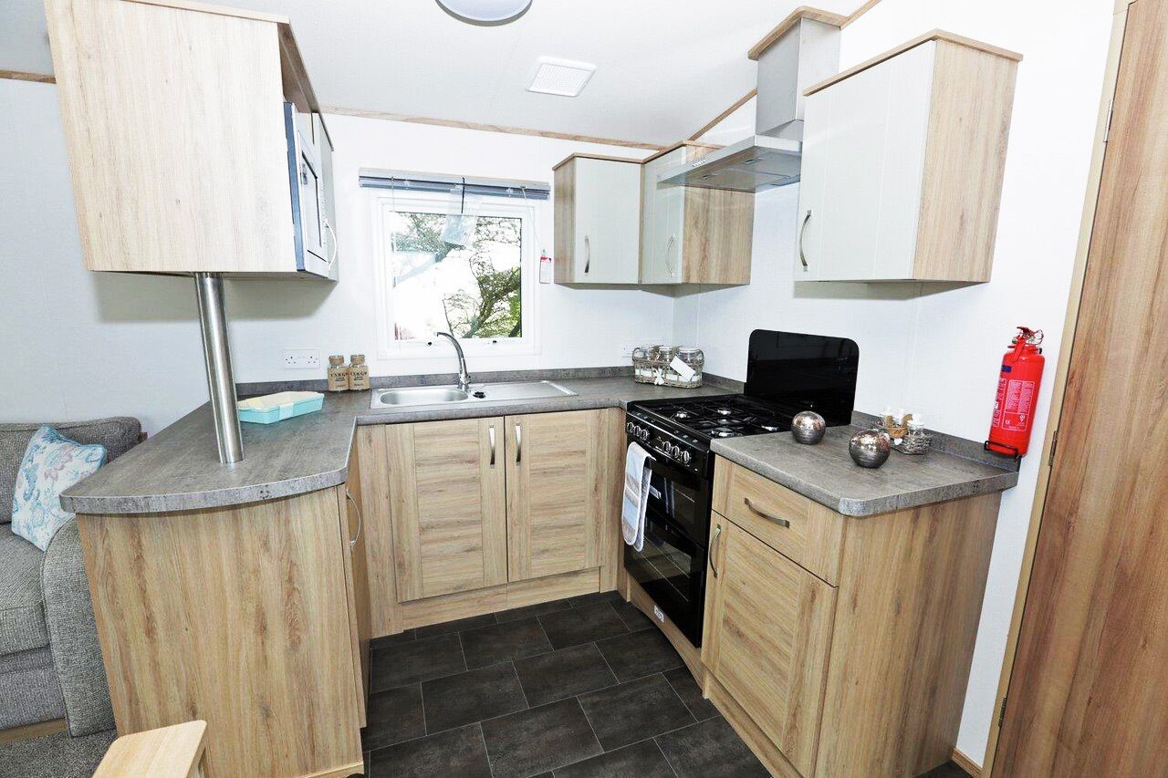 Una cocina compacta con muebles de madera, una estufa negra y un ventanal.