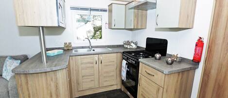A compact kitchen with wooden cabinets, a black stove, and a window.
