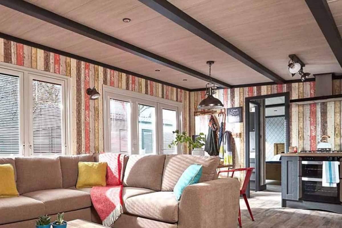 A living room with a beige sofa, colorful cushions, and striped wallpaper.
