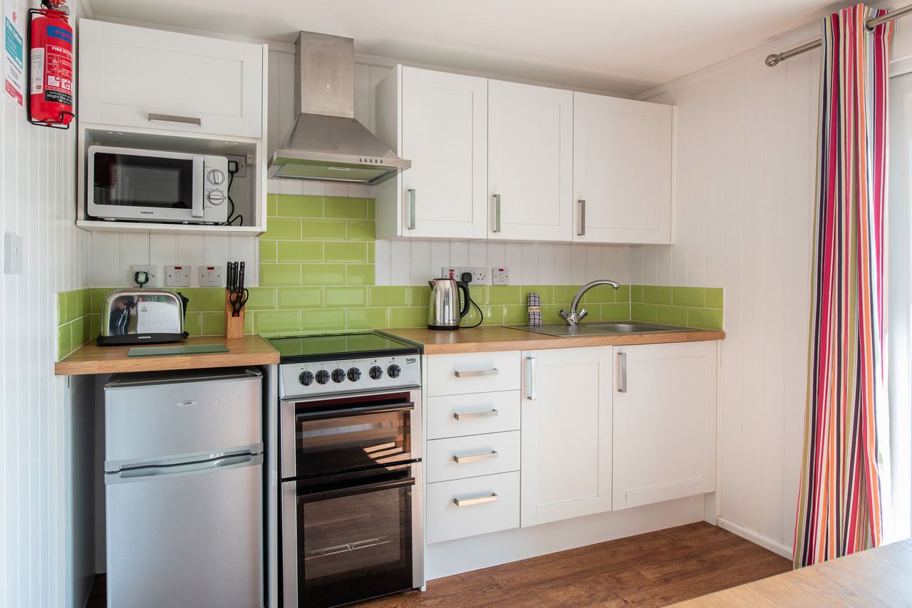 A compact kitchen with white cabinets, a microwave, a stove, and a refrigerator.