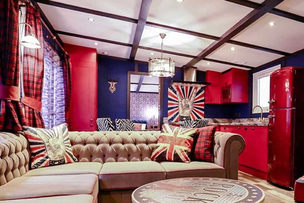 A modern living room with a sofa, a red refrigerator, and a television.