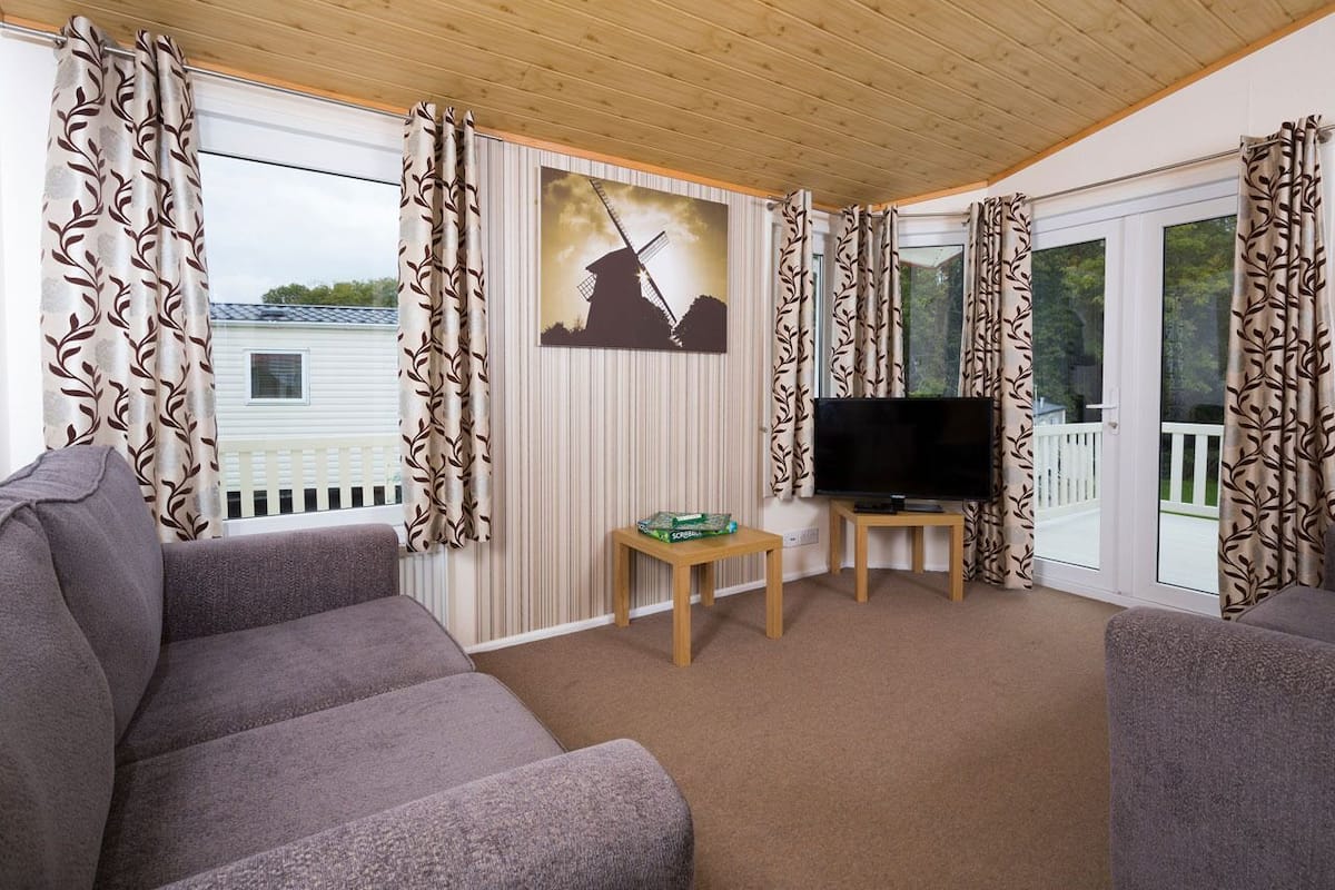 A cozy living room with a flat-screen TV, a sofa, and a painting of a windmill.