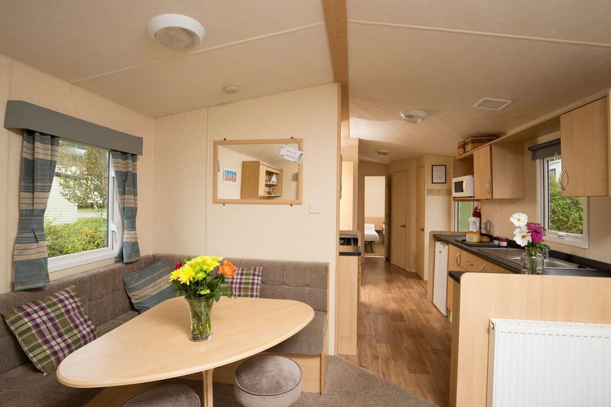 A compact RV interior with a dining area, kitchenette, and a small bathroom.