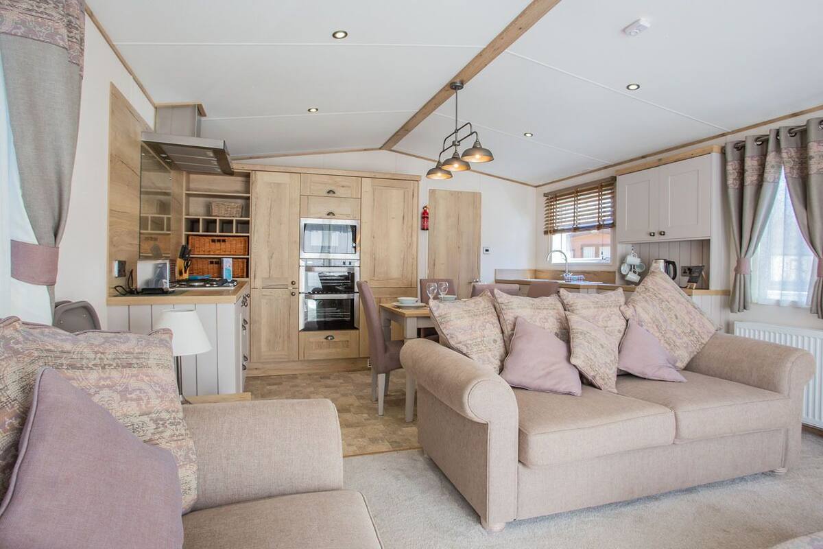 A cozy living room with a sofa and armchairs, a dining area with a table and chairs, and a kitchen with wooden cabinets and appliances.