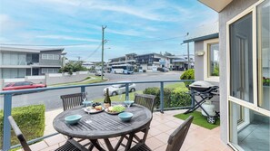 Enjoy al fresco dining on this balcony with a grill and barbecue, overlooking a residential area with modern buildings.