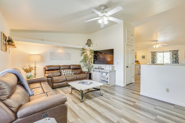 A spacious living room with a brown leather sofa, a white coffee table, and a ceiling fan. - Hike, Sled & Snowshoe! Family Retreat in Payson (Payson)