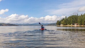 A kayaker on a calm lake with mountains and a forested area in the background. - Hochwertige Studios für Monteure (Stemshorn)