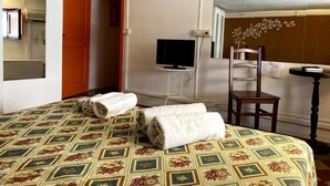 A hotel room with a bed, a television, a chair, and a small table. - Economy Double Room - Interior floor (Catania)