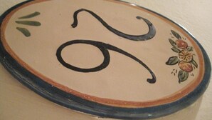 A ceramic plate with a decorative design, including a stylized letter 'S' and a floral pattern. - Economy Double Room - Interior floor (Catania)