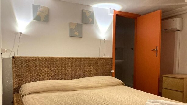 A hotel room with a bed, a wooden headboard, a wardrobe, and a bathroom visible through an open door. - Economy Double Room - Interior floor (Catania)