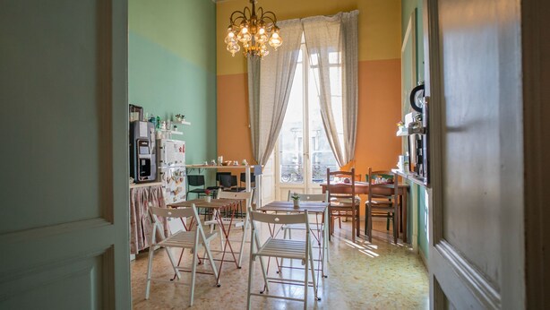 Un coin repas comprenant une table et des chaises, un lustre et une fenêtre avec des rideaux.
