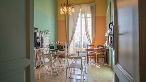 A dining area with a table and chairs, a chandelier, and a window with curtains. - Double or Twin Room (Catania)
